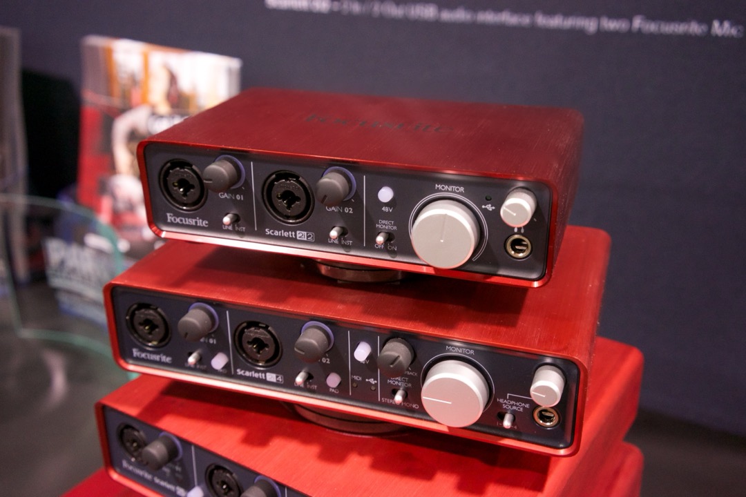 Focusrite Scarlett 2i2, 2i4 and 6i6 USB audio interfaces lined up on a display counter, showing their front-panel gain knobs and combo XLR inputs