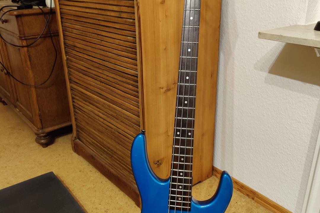 Beginner electric bass guitar with a Precision-style body resting against a practice amp