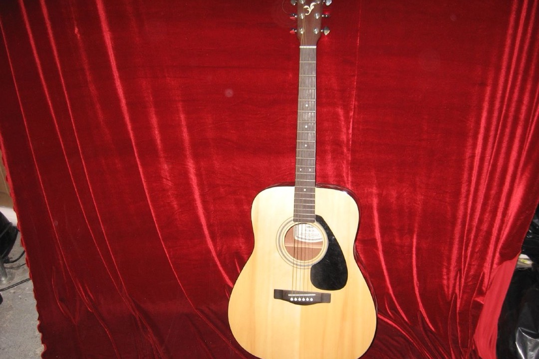 Beginner dreadnought acoustic guitar with a spruce top resting against a wooden chair