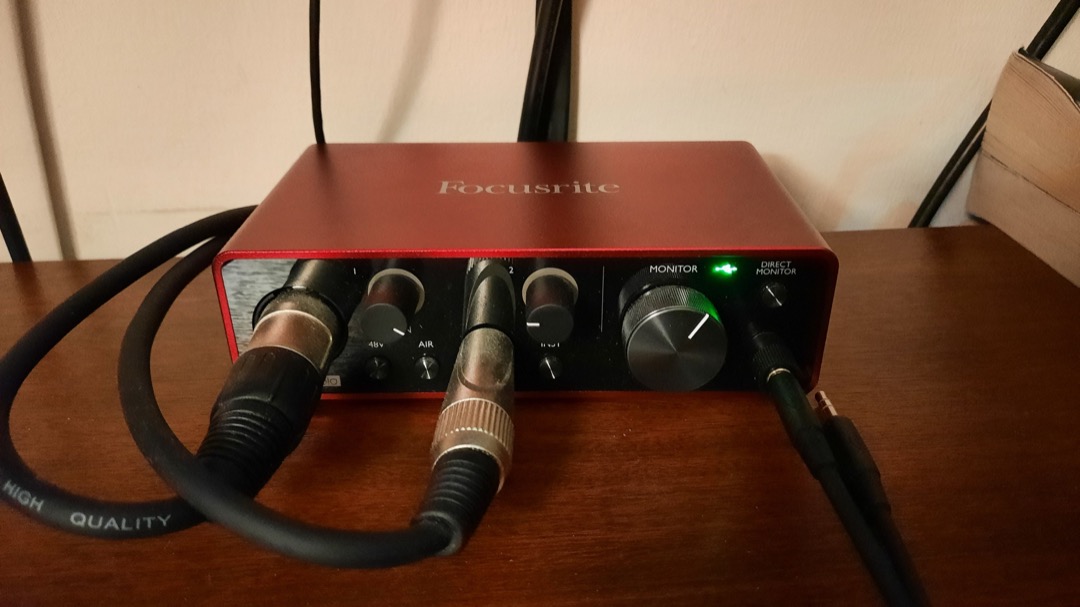 Focusrite Scarlett Solo compact USB audio interface on a desk, showing its front-panel gain knob, combo XLR input and instrument input