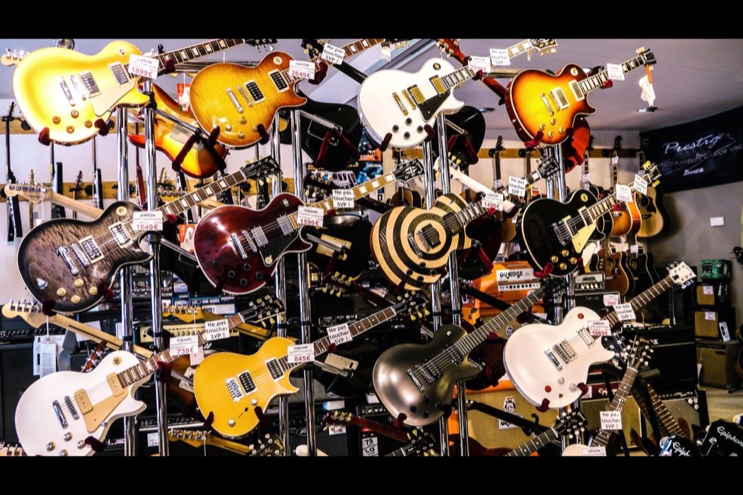 A wall of electric guitars in a guitar shop, showing the range of body shapes and finishes a buyer chooses between