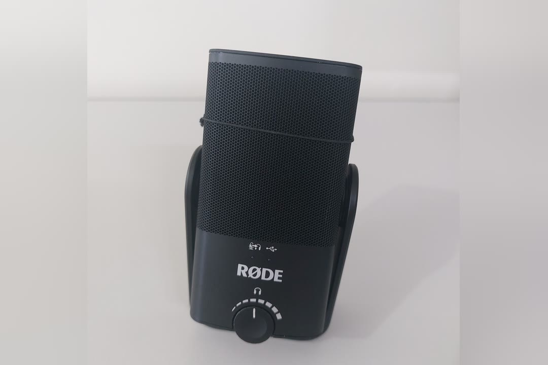 A RØDE NT-USB Mini USB condenser microphone on its magnetic desktop stand, with the headphone level knob on the front