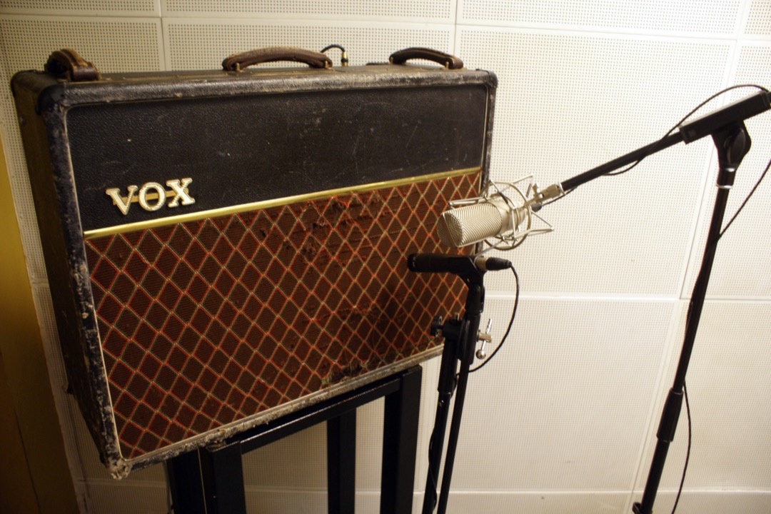 A Shure SM57 dynamic microphone and a shock-mounted large-diaphragm condenser microphone set up side by side in front of a Vox AC30 guitar amp