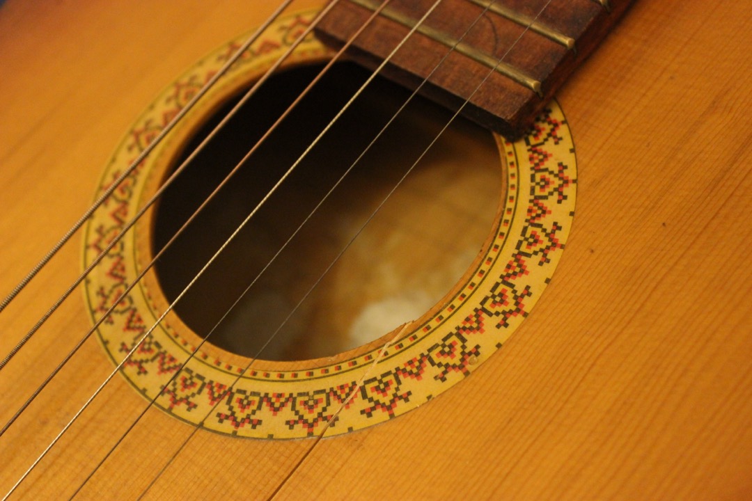 Close-up of the six strings and tuning pegs on an acoustic guitar headstock