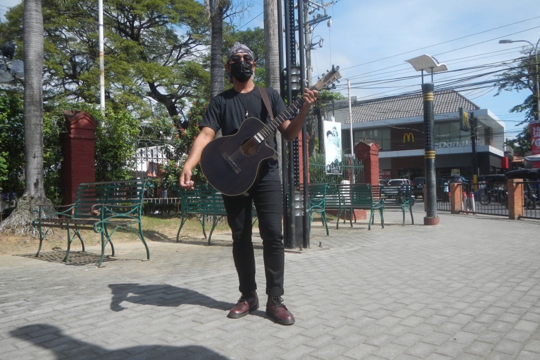 A beginner seated with an acoustic guitar, fretting a chord on the neck