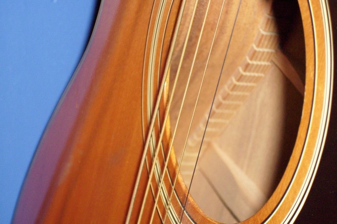 Close-up of the six strings of an acoustic guitar over the sound hole